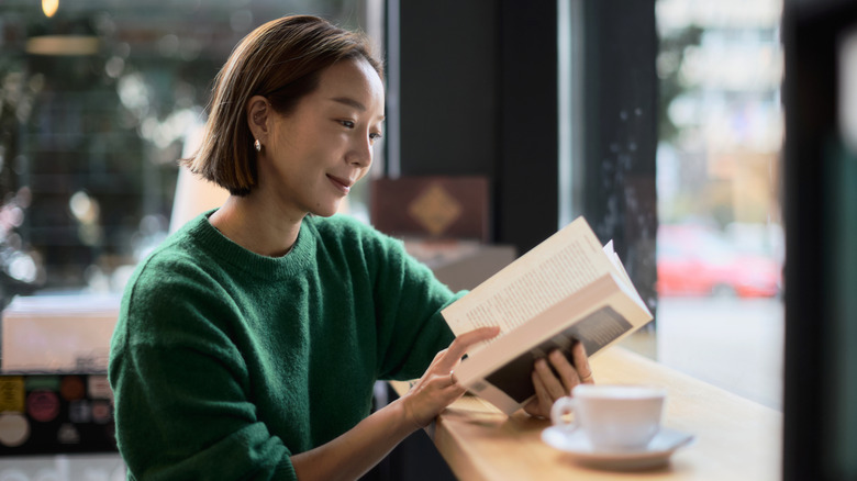 A young woman in a cafe reading a book