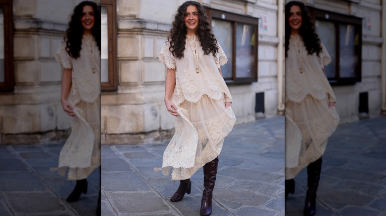 A woman in a white midi skirt with tall dark leather boots