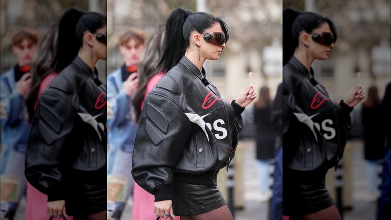 A woman in a black leather Moto jacket and sunglasses