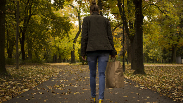 A woman from behind walking in skinny jeans and a green jacket