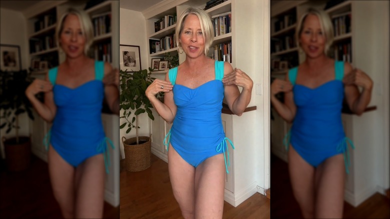 A woman posing indoors in a blue, ruched swimsuit