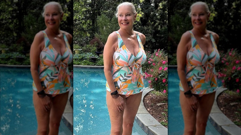 A woman posing by a swimming pool in a multi-colored tankini