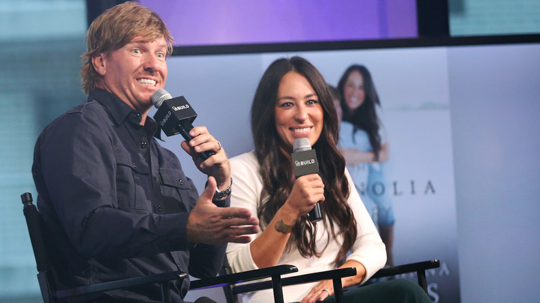 Chip and Joanna Gaines on stage both holding microphones