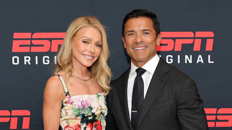 Kelly Ripa in a floral dress and Mark Consuelo stood in a black suit