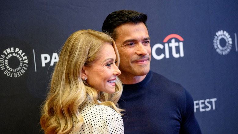 Kelly Ripa in a white spotty dress and Mark Consuelo stood in a blue jumper