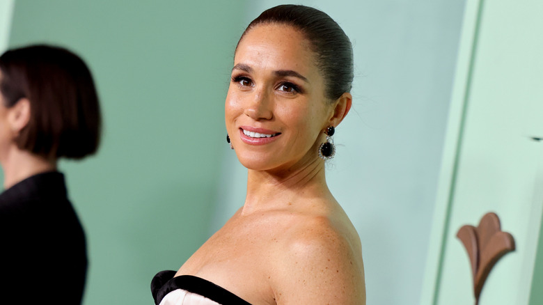 Tilted snapshot of Meghan Markle attending a 2026 gala in a strapless gown and pulled-back hairstyle