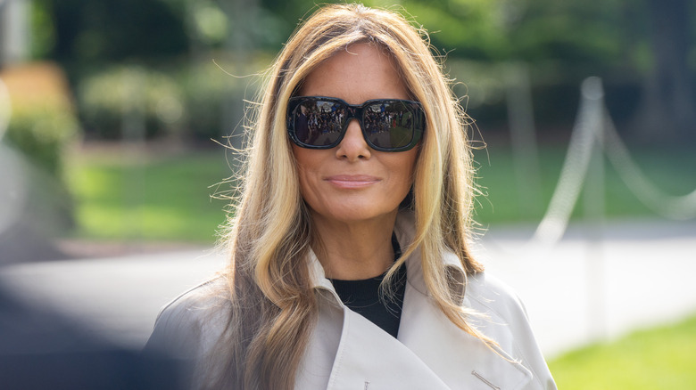 Melania Trump in a white trench coat and sunglasses