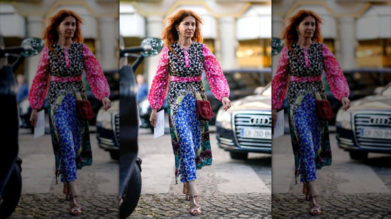 A colorfully dressed older woman walking in the street