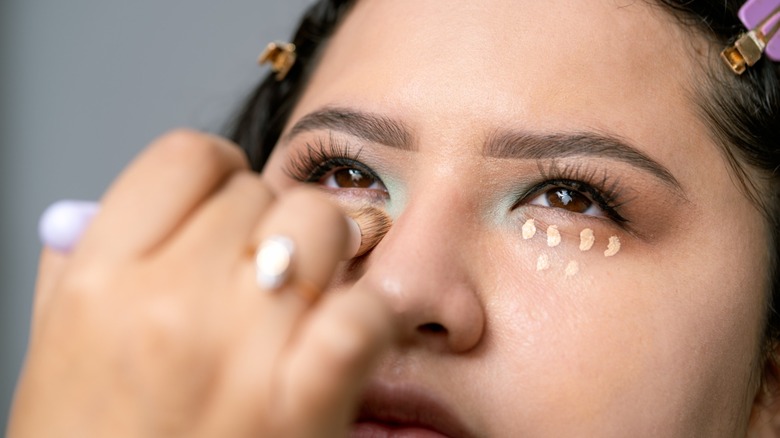 A woman with hooded eyes having makeup applied