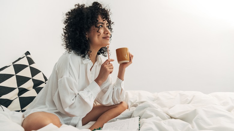 Woman journaling in bed with coffee