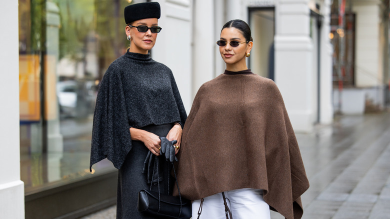 Two women on the streept wearing knit capes