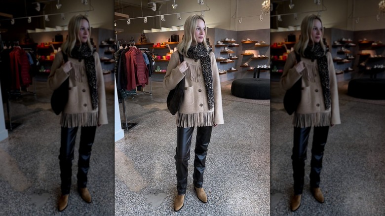 A woman wearing a fringed jacket with slim leather pants and a scarf