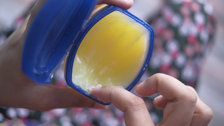 Person scooping Vaseline with finger