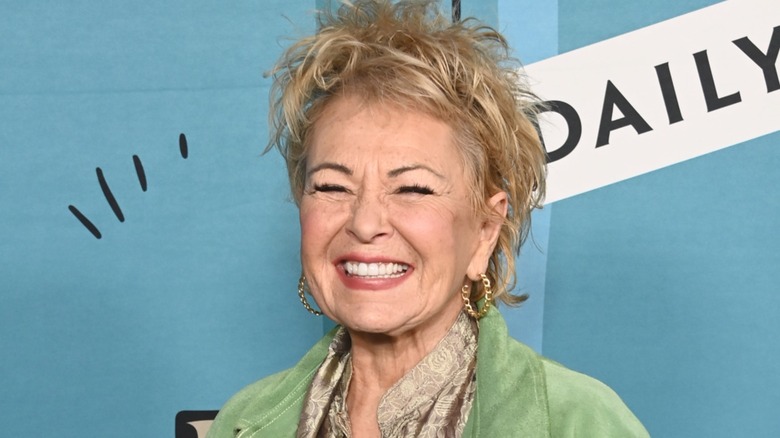 Roseanne Barr smiling on the red carpet in front of a blue background