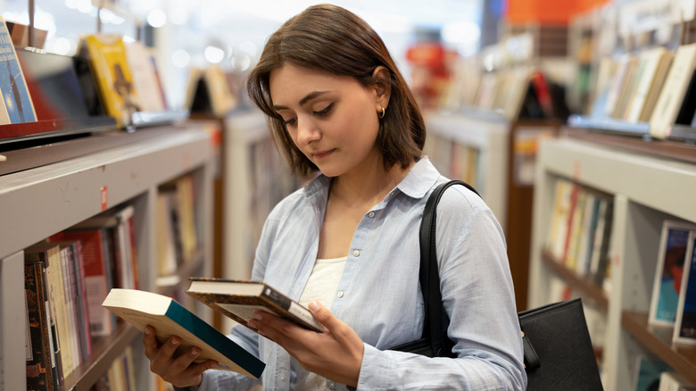 Woman deciding between two books at a bookstore