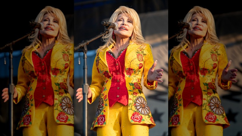 Dolly Parton on stage in an embroidered yellow and red suit