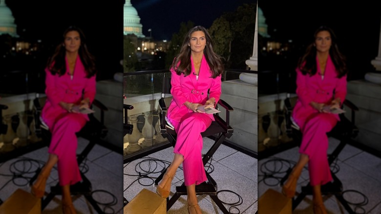 Kaitlan Collins sitting in a chair outside while wearing a hot pink pantsuit