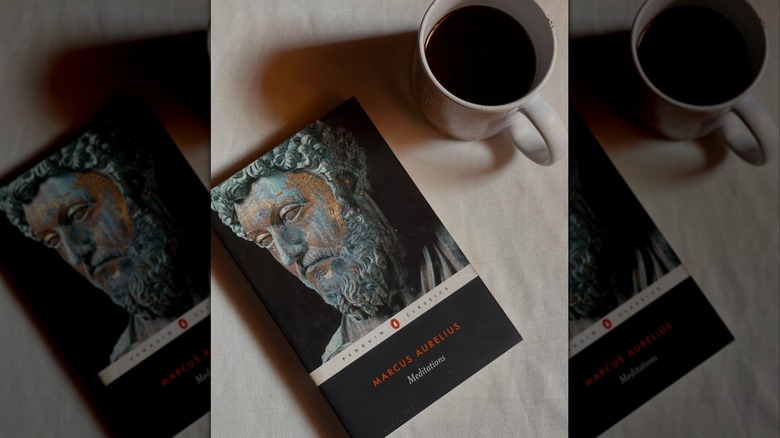 A copy of "Meditations" laying next to a cup of black coffee