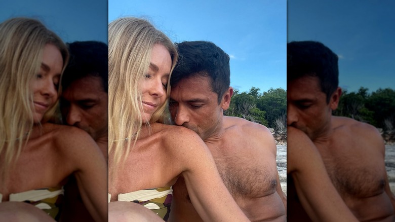 Kelly Ripa receiving a kiss on the shoulder from Mark Consuelos on a beach