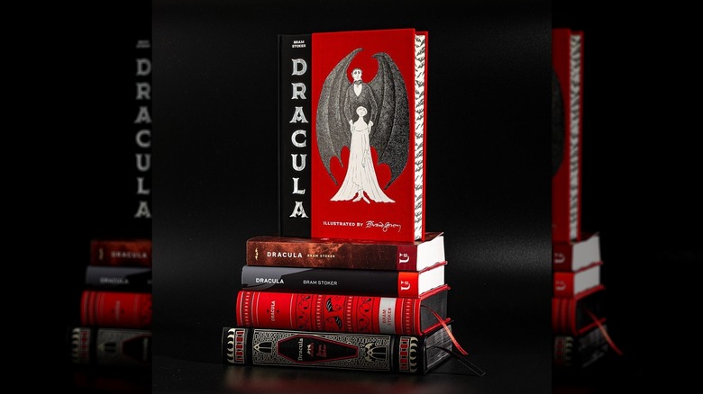 A stack of books featuring different versions of "Dracula by Braun Stoker," including a standing red-and-black copy on top
