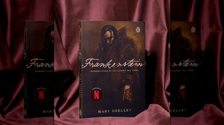 A movie-cover version of "Frankenstein" styled against a pinkish-red cloth backdrop