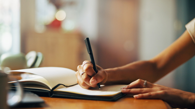 A close up of a woman writing in her journal