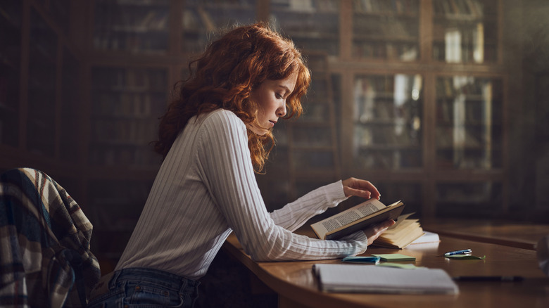 A woman with red hair reading in a library