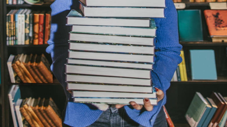 Woman peeking over large stack of books