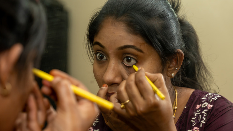 Woman putting eyeliner on waterline