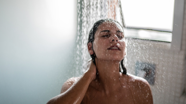 A woman in a black bra brushing wet hair after a shower