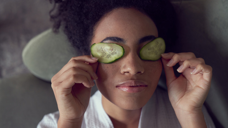 Woman lying down with cucumbers on eyes