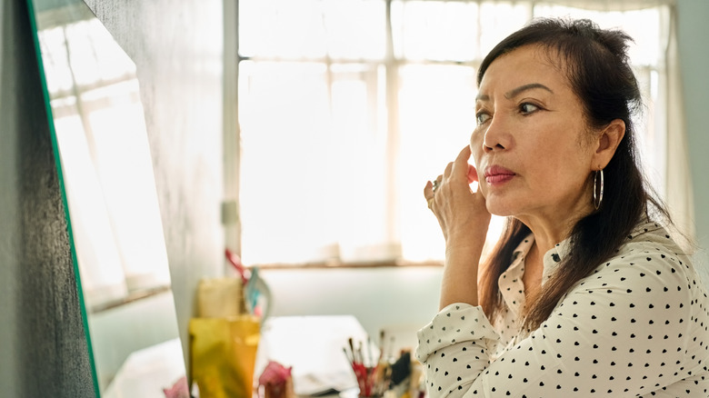 Older women looking in mirror wearing blouse with heart polka dots