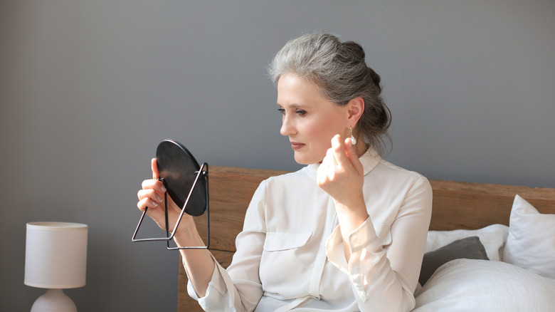 Older women admiring her makeup in a small mirror