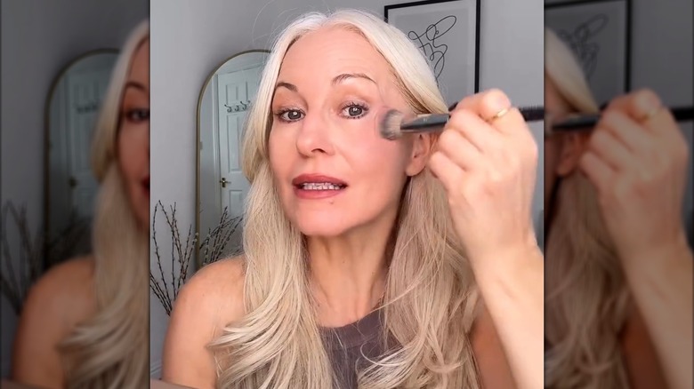 An older woman applying blush