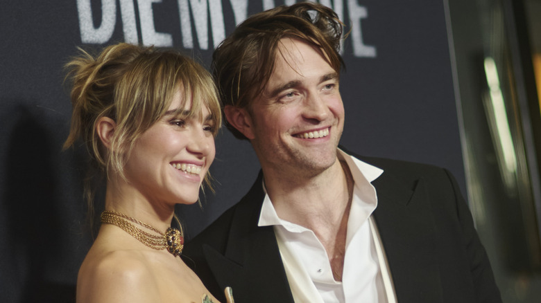 Suki Waterhouse and Robert Pattinson smiling while posing together at a New York City premiere