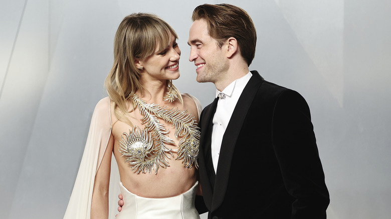 Suki Waterhouse and Robert Pattinson smiling into each other's eyes while posing at the 2026 Vanity Fair Oscar Party