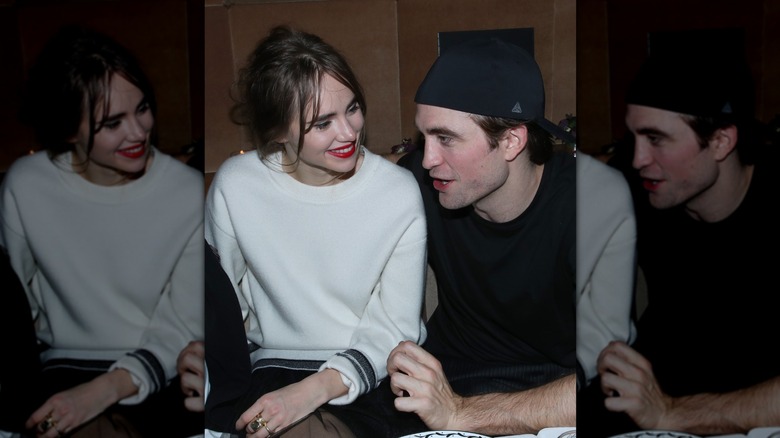 Suki Waterhouse looking adoringly at Robert Pattinson as he speaks to someone out of frame at a Dior Perfume Dinner