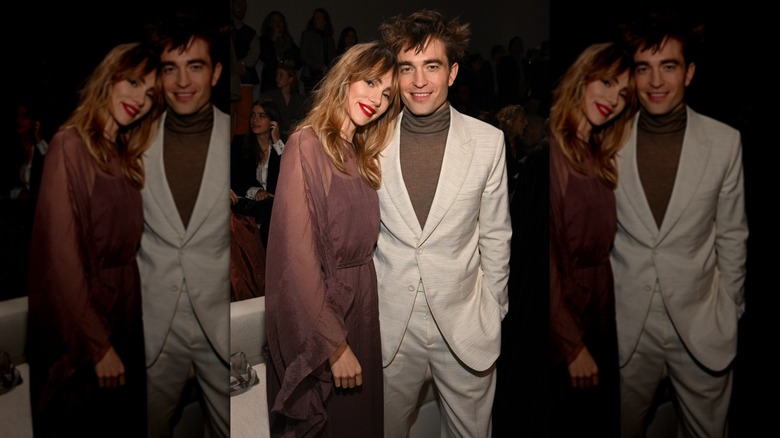 Suki Waterhouse leaning against a smiling Robert Pattinson at the Dior Fall 2023 Menswear Collection