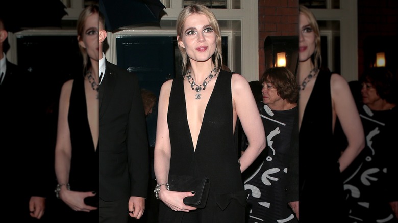 Lucy Boynton smiling at as she arrives at a movie premiere while wearing a bold eye makeup look