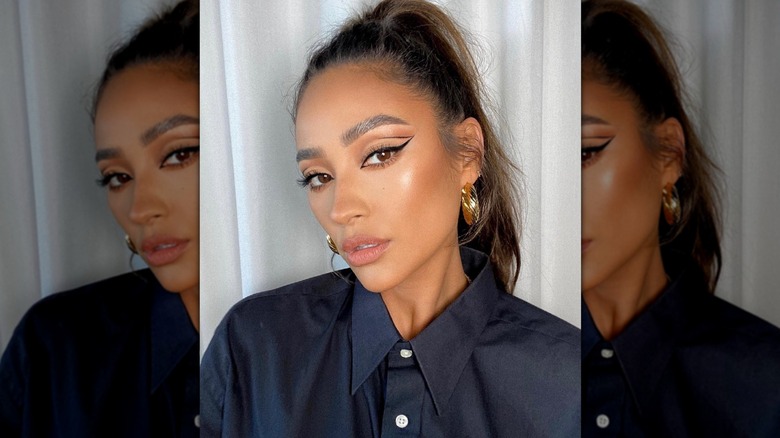 Shay Mitchell posing with a sleek winged eyeliner look featuring a cut-crease detail