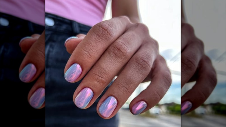 A woman's hand with a pink and purple chrome manicure