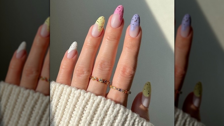 Close-up of a single hand showing a colorful and speckled nail design