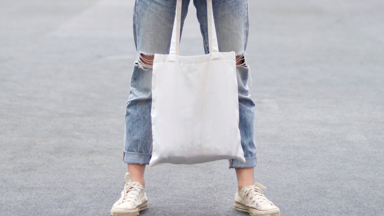 person holding white tote bag