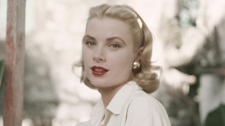Grace Kelly, wearing red lipstick, posing during a photoshoot with a neutral expression