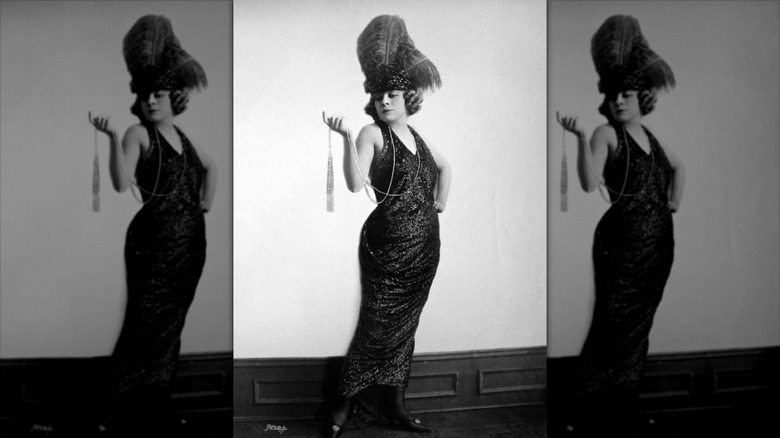 Black and white photo of Mae West in a sequin dress and feather headdress