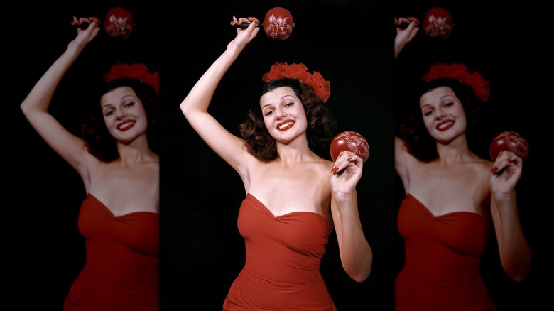 Rita Hayworth posing with maracas in a monochrome red outfit