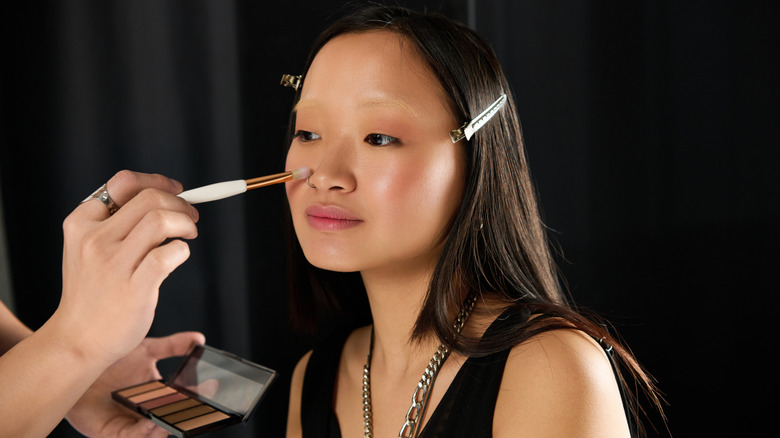 Makeup artist applies makeup to model