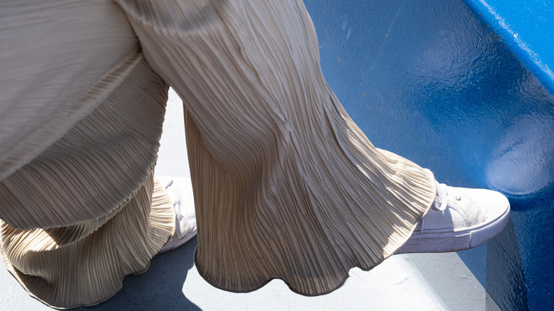 Woman wearing beige wide-legged pants with white sneakers