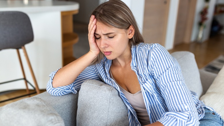 A woman looking distressed while resting her head in her hand