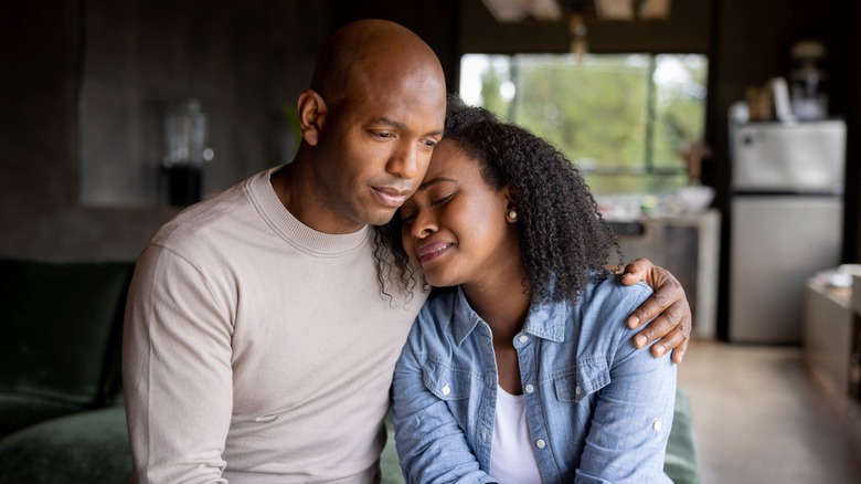 A couple, including a distressed woman, embracing